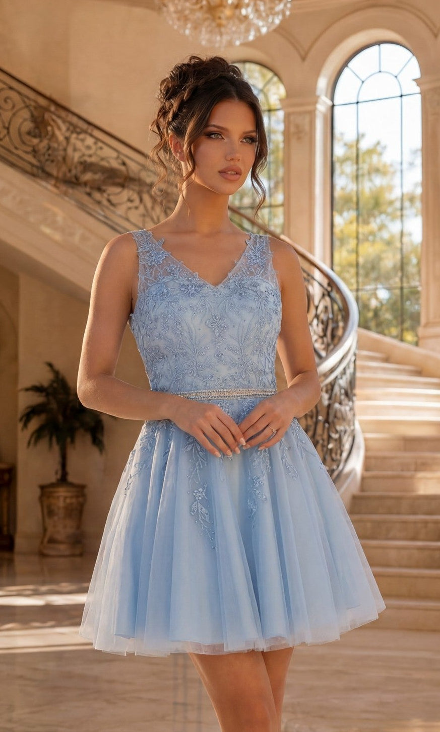 A woman wearing a Bahama Blue Short Prom Dress with an Embroidered Sheer Bodice stands by a curved staircase in a spacious, elegant interior with large windows.